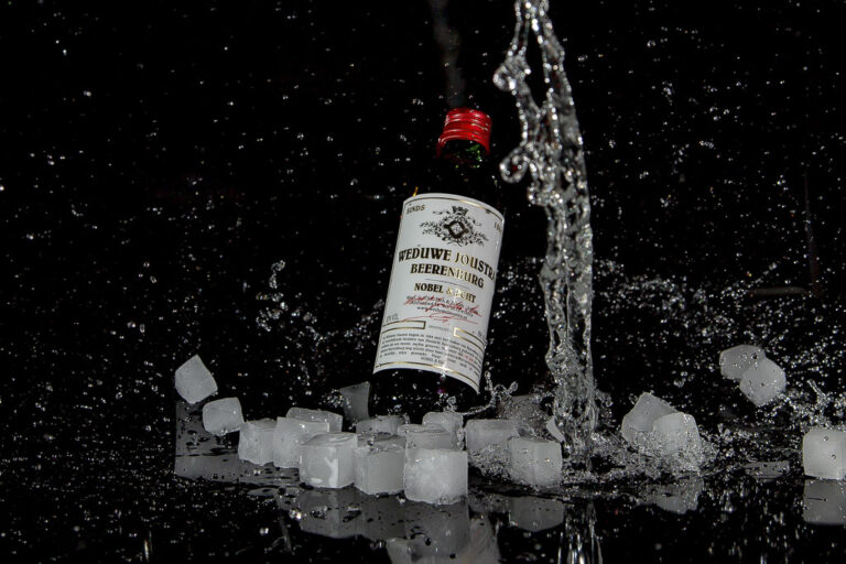 Fles met opspattend water en ijsblokjes – productfotografie
